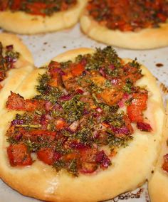 small pizzas with various toppings sitting on a baking sheet