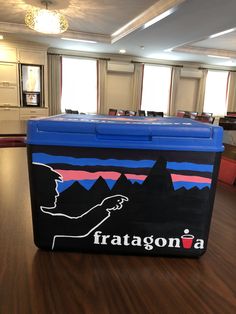 a large blue cooler sitting on top of a wooden table in a room with windows