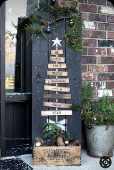 a christmas tree made out of wooden planks on the front porch with evergreen and pine cones