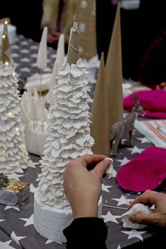 a person is decorating a small white christmas tree on a table with other decorations