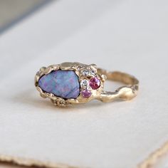 "Our one-of-a-kind 14k yellow gold boulder-opal ring celebrates the natural beauty of this incredible gemstone, a rare specimen with electric flashes of candy-pink, raspberry-red, lime and tangerine on a smoky lavender-blue field. Accents of pink sapphires, white diamonds and tanzanite bring out the sparks of bright color, with a gracefully undulating branch band and hand-hammered texture to emphasize the opal's slightly rustic nature. Organic minimalism with a brutalist vibe. It's designed to s Rough Opal Ring, Brutalist Ring, Organic Minimalism, Antique Opal Ring, White Rings, Boulder Opal Ring, Pink Raspberry, Tanzanite Diamond, Raspberry Red