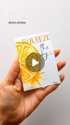 a hand holding up a piece of paper with an orange slice on it that says squeezeeze the day