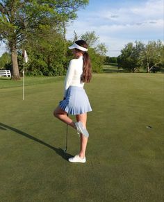 a woman standing on top of a green holding a golf club