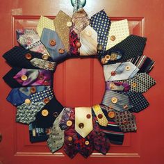 a wreath made out of ties and buttons on a door frame with a christmas ornament hanging from it