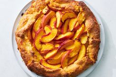 a pie with sliced peaches on it sitting on a plate