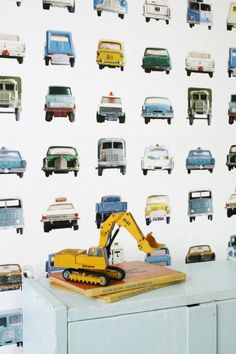 a wall with cars and trucks on it next to a blue dresser in front of a white wall