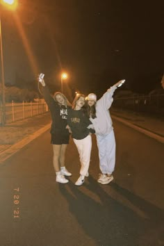 two young women standing on the side of a road holding their arms in the air