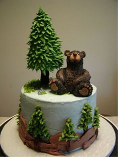 a cake with a bear sitting on top of it next to a small pine tree