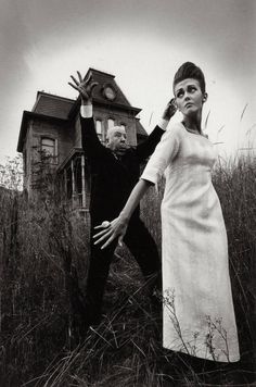 a man and woman dressed up as zombies in front of a house with hands outstretched