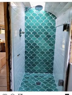 a bathroom with green tiles on the shower wall