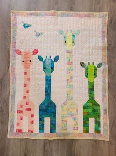 three giraffes are standing next to each other on a wall hanging quilt