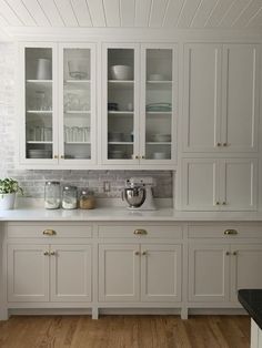 a kitchen with white cabinets and wood floors