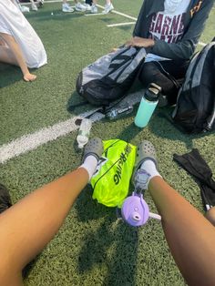 two people sitting on the ground with sports equipment and water bottles in their hands,