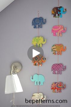 an elephant mobile is hanging on the wall next to a lamp and lampshade