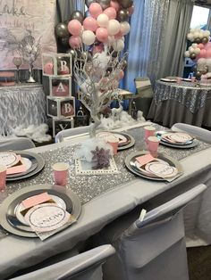 a table set up for a baby shower with pink, silver and white balloons in the background