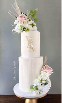 a three tiered white wedding cake with flowers on top