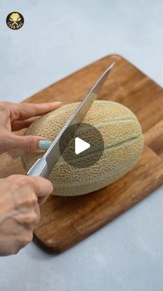 a person cutting melon on a wooden cutting board