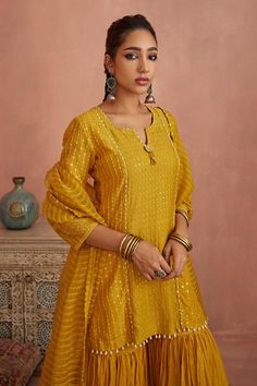 Yellow chanderi short kurta with thread embroidery. Comes with gharara and an organza dupatta.
Components: 3
Pattern: Embroidered
Type Of Work: Thread
Neckline: Notched
Sleeve Type: Three quarter
Fabric: Chanderi, Dupatta: Organza
Color: Yellow
Other Details: 
Length:
Kurta: 31 inches
Gharara: 42 inches
Note: Ivory outfit worn by the other model is not for sale.
Occasion: Mehendi and Haldi - Aza Fashions Festive Chinon Sharara With Straight Kurta, Festive Chikankari Embroidered Dola Silk Sharara, Chanderi Sharara With Mirror Work And Straight Kurta, Sharara With Gota Work And Straight Kurta In Chinon, Chinon Sharara With Gota Work And Straight Kurta, Raw Silk Sharara With Chikankari Embroidery, Chanderi Sharara With Dori Work Straight Kurta, Festive Straight Kurta Sharara With Dori Work, Straight Kurta Sharara With Resham Embroidery For Navratri