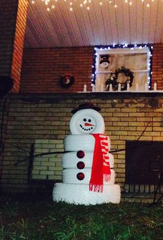 a large snowman sitting in front of a brick fireplace