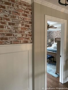 an open door leading to a bedroom with a brick wall and ceiling fan in it