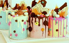 three decorated cakes sitting on top of a white tray covered in frosting and toppings