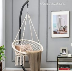 a hammock hanging in a living room next to a table with a vase on it