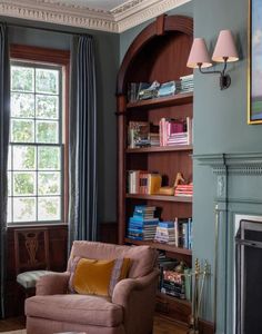 a living room filled with furniture and a fire place in front of a book shelf