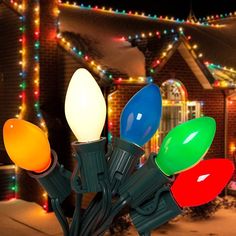 christmas lights in front of a house with holiday decorations on the roof and around it