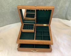 an open wooden jewelry box sitting on top of a bed