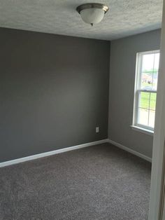 an empty room with gray walls and carpet