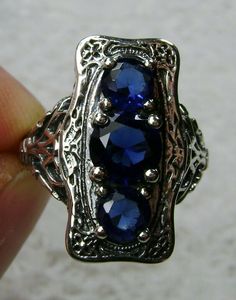 "Simulated Blue Sapphire Ring 3Stone Rectangle#60 Custom Made This is a lovely late Victorian era reproduction ring in solid sterling silver. The gorgeous filigree ring is set with 3 round-cut simulated blue sapphire gemstones. The 2 smaller blue sapphire gems are 4.5mm in diameter, and the center one is 6mm in diameter. This filigree setting is a casting from an actual Antique ring; notice the amazing etched band... The ring sits 3/4th\" (19mm) NS on the finger. The quality of the silver and ge Silver Three-stone Sapphire Jewelry, Vintage Sapphire Three Stone Ring, Silver Sapphire Three Stone Jewelry, Silver Three Stone Sapphire Jewelry, Blue Three Stone Sapphire Ring In Sterling Silver, Antique Blue Multi-stone Jewelry, Antique Silver Three Stone Jewelry, Sterling Silver Sapphire Three-stone Jewelry, Sapphire Three Stone Sterling Silver Jewelry