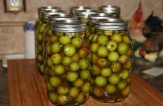 three jars filled with green apples sitting on top of a counter