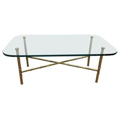 a glass and brass coffee table with metal legs