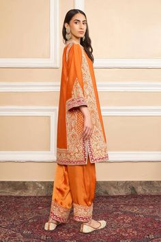 Orange pure silk chanderi A-line kurta with gota applique and kashmiri tilla embroidery. Comes with bamberg satin salwar and a silk organza dupatta with kinari finish.
Component: 3
Pattern: Embroidered
Type Of Work: Gota applique, Kashmiri tilla
Neckline: Band collar
Sleeve Type: Three quarter
Fabric: Kurta : Pure silk chanderi, Salwar : Bamberg satin, Dupatta : Silk organza
Color: Orange
Other Details: 
Short slits
Embroidered border at hem
Buttoned placket
Occasion: Mehendi and Haldi, Sangeet Transitional Silk Kurta With Dabka Detailing, Transitional Cotton Silk Palazzo Set With Dabka, Transitional Silk Straight Kurta, Festival Kurta In Slub Silk With Dabka Work, Festival Slub Silk Kurta With Dabka Work, Transitional Raw Silk Kurta With Dupatta, Semi-stitched Cotton Silk Dress With Cutdana, Slub Silk Kurta With Zari Work In Traditional Drape, Designer Slub Silk Kurta With Resham Embroidery