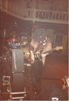 a man with a hat playing guitar on stage