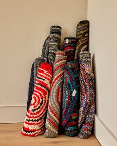 a pile of colorful knitted items sitting on top of a wooden floor next to a wall