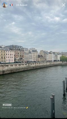 a river with buildings on the side and water in front of it, under a cloudy sky