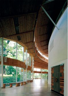 the inside of a building with large windows and wood paneling on the ceiling is empty