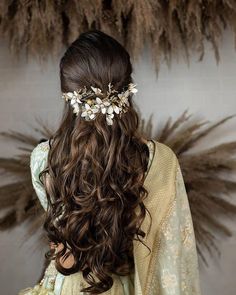 the back of a woman's head with long hair and flowers in her hair