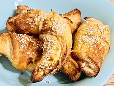 a blue plate topped with pastries covered in sesame seeds