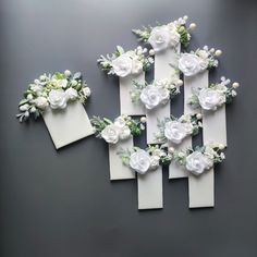 several pieces of paper with white flowers and greenery attached to them on a gray surface