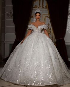 a woman in a white wedding dress standing next to a window