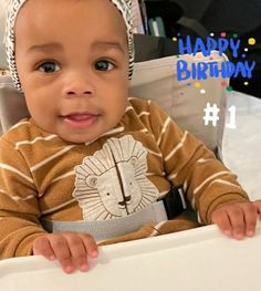 a baby sitting in a high chair with a happy birthday card on it's back