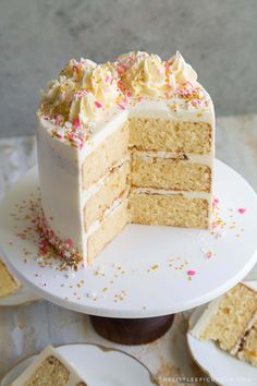 a cake with white frosting and sprinkles sits on a plate next to other plates