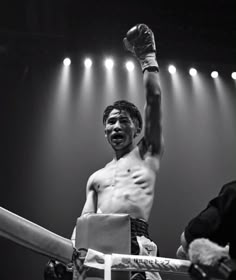 a black and white photo of a man holding a boxing glove up in the air