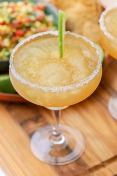 two margaritas sitting on top of a wooden table