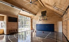 an indoor basketball court with wood paneling and glass doors on the side wall is shown