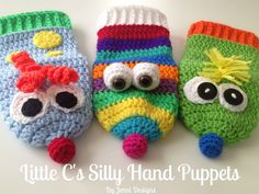 three crocheted little monster mittens with googly eyes and one wearing a hat