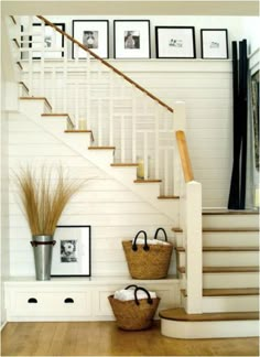 two baskets on the floor in front of stairs with pictures on the wall behind them