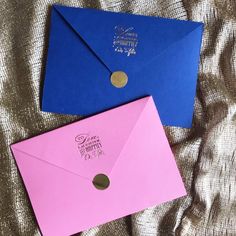 two pink and blue envelopes sitting on top of a bed